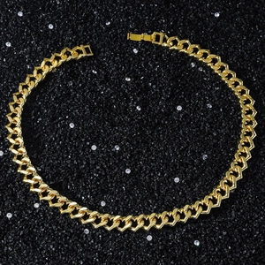 Close-up of gold heart Cuban link chain with fold-over clasp on black stone background