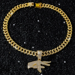 Close-up of gold iced-out hip hop hand sign pendant with heavy Cuban link chain texture