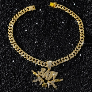 Détail macro de la chaîne Cuban dorée et pendentif BABY avec deux fusils AK-47