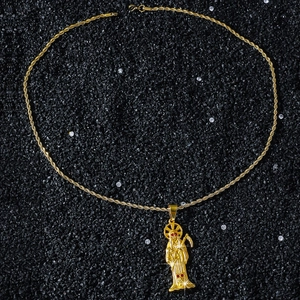Close-up of gold grim reaper pendant with red crystals and twisted rope chain necklace