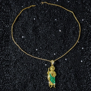 Detailed close-up of Saint Jude pendant with green enamel and gold twisted chain on black stones