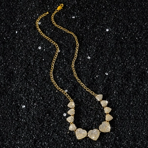 Golden hip-hop chain necklace featuring iced-out crystal hearts on black sand background
