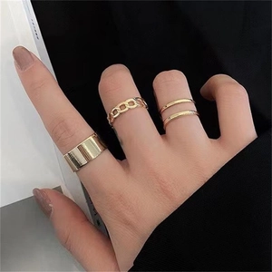 Detailed view of three gold-plated chain link and polished stackable rings on hand