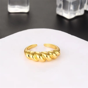 Macro detail of gold-plated croissant ring showing a twisted spiral texture and open band