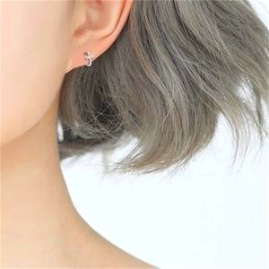 Gros plan de boucles d'oreilles croix en argent S925 avec zircons brillants sur un modèle