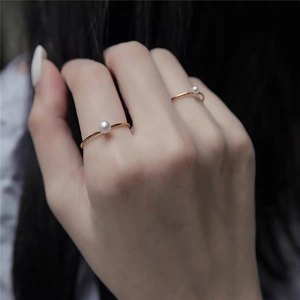 Close-up of elegant gold S925 silver rings with round white pearls on a model's hand