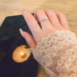 Close-up of minimalist S925 silver gold-plated ring with a round white pearl on finger