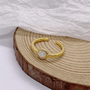 Anello minimalista in argento S925 dorato con opale su un espositore in legno