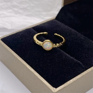 Dettaglio anello aperto dorato con trama martellata e pietra d'opale in una scatola regalo