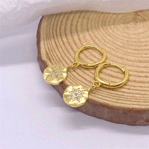 Macro detail of gold-plated S925 sterling silver drop earrings with starburst engraving