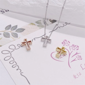 Trois pendentifs croix évidés en argent, or et or rose sur une carte florale décorative
