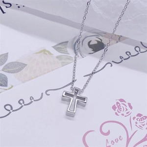 Détail macro du collier pendentif croix évidée en argent sur fond floral esthétique