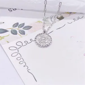 Macro detail of S925 sterling silver sun coin pendant on a paper clip link chain necklace