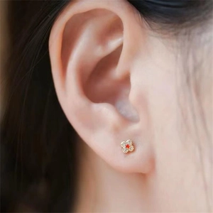 Elegant gold-plated S925 silver four-leaf clover stud earrings with red stone on model