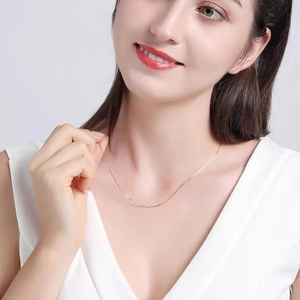 Gros plan d'un collier chaîne croisée en argent S925 plaqué or porté par un mannequin