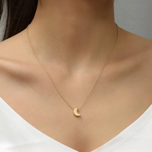 Close-up of minimalist gold crescent moon pendant on a fine chain worn by a model