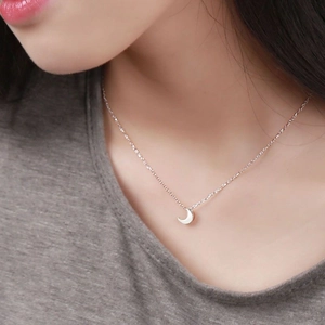 Close-up of minimalist S925 sterling silver moon pendant necklace worn by a model