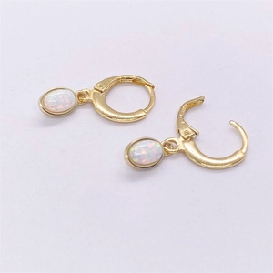 Macro shot of gold S925 sterling silver earrings with oval white opal stones and lever backs