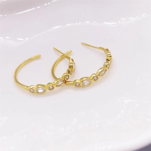 Détail des boucles d'oreilles créoles en argent doré avec zircons en forme de marquise