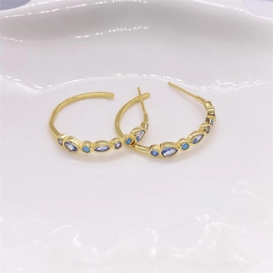 Détail des créoles en argent 925 doré avec des pierres précieuses bleues poires