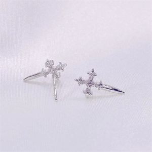 Macro detail of gothic S925 sterling silver cross dagger stud earrings on silk