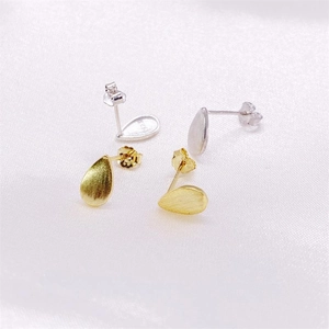 Macro detail of brushed S925 sterling silver teardrop earrings in gold and silver