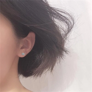Detail of cute blue whale stud earring with gold plating worn on earlobe