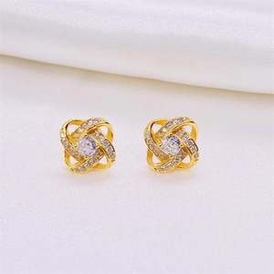 Macro detail of gold-plated rotating clover earrings with sparkling pavé micro-diamonds