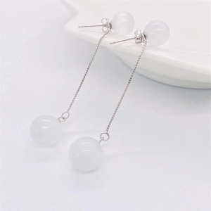 Macro shot of S925 sterling silver tassel earrings with white opal beads on a white tray