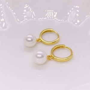 Macro shot of gold-plated S925 silver hoop earrings featuring white pearl pendants