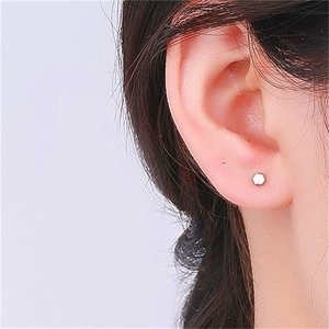 Close-up of minimalist S925 sterling silver plum blossom stud earring on a female ear
