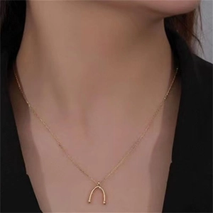 Gros plan d'un collier pendentif fer à cheval en argent S925 doré porté au cou