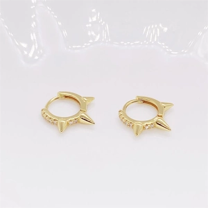 Macro view of gold-plated punk spike hoop earrings with white zircon inlays