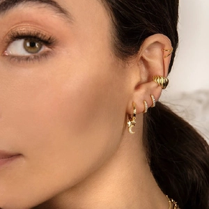 Detailed view of women wearing gold celestial hoop earrings and crystal ear cuffs set