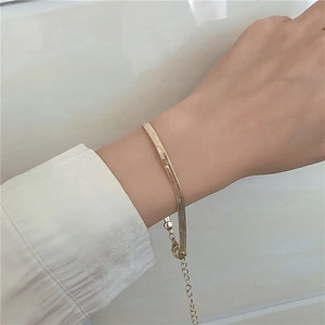 Détail d'un bracelet maille serpent dorée au poignet avec une chemise blanche