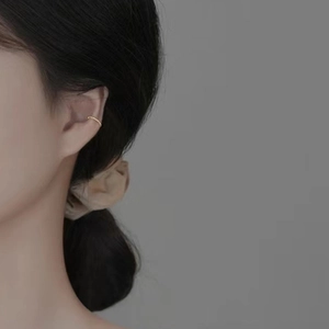 Détail d'un earcuff torsadé doré avec texture perlée porté par un mannequin femme
