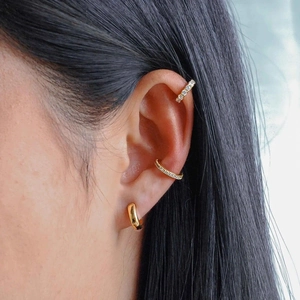 Détail de manchettes d'oreilles en argent S925 et d'une boucle d'oreille dorée sur modèle