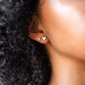 Gros plan de boucles d'oreilles cœur et opale en argent S925 sur l'oreille du mannequin