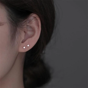Macro shot of minimalist S925 sterling silver star stud earrings worn on female ear