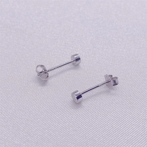 Macro shot of minimalist S925 sterling silver stud earrings on purple silk background