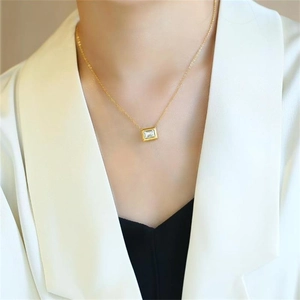 Close-up of a minimalist gold square pendant necklace with a rectangular cut zircon stone