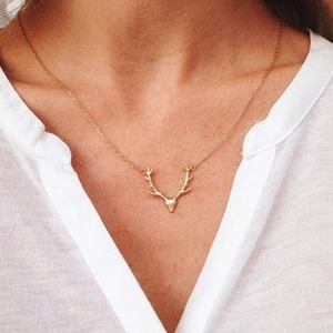 Close-up of elegant gold deer antler pendant necklace worn on female neck