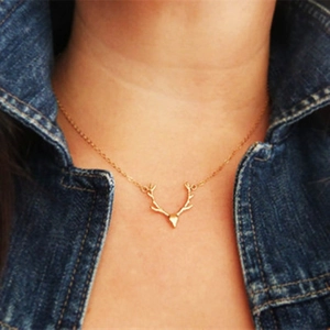 Detailed close-up of golden reindeer antler pendant necklace on female collarbone