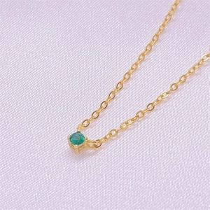 Elegant gold S925 silver necklace with a green zircon pendant on purple silk background