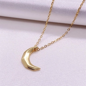 Vue détaillée d'un pendentif lune dorée aux facettes géométriques sur du satin blanc