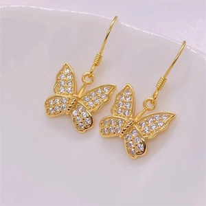 Elegant gold butterfly drop earrings with white zircon accents on white ceramic background