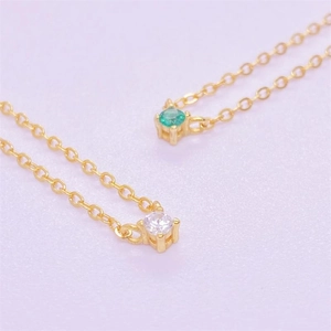 Macro detail of gold S925 silver necklace with green zircon and clear stone pendants