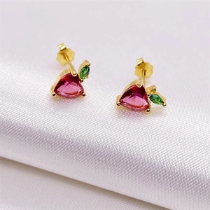 Close-up of S925 silver apple studs with red heart zircon and green leaf on white satin