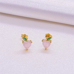 Detail of S925 silver peach fruit stud earrings with pink heart and green gems on silk