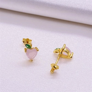 Macro view of gold-plated S925 silver earring with pink heart stone and green leaf gem
